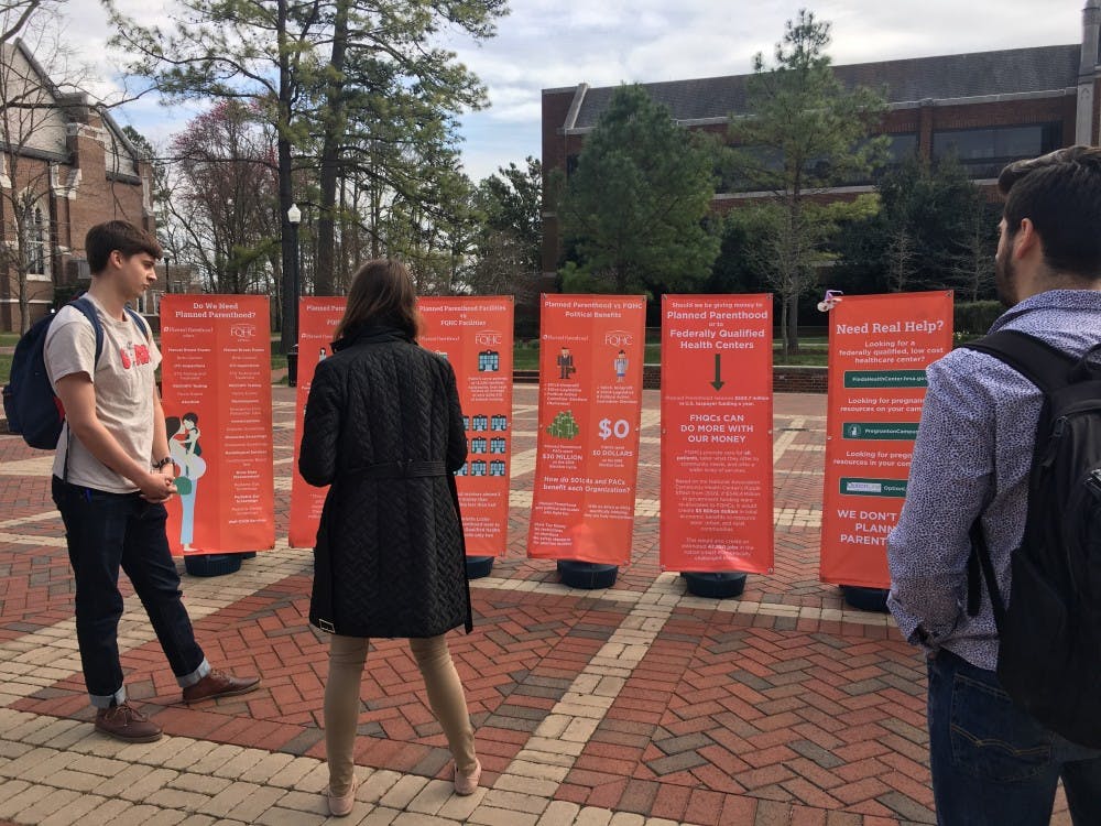 Sophomore&nbsp;Liam Rose&nbsp;&nbsp;stands with a representative from Spiders for Life to discuss the information presented on the posters.&nbsp;