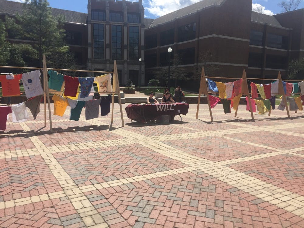 <p>Members of WILL*,&nbsp;Hannah Dunn, WC '19, and&nbsp;Kylie Britt, WC '19, sit in between displays of the Clothesline Project.</p>