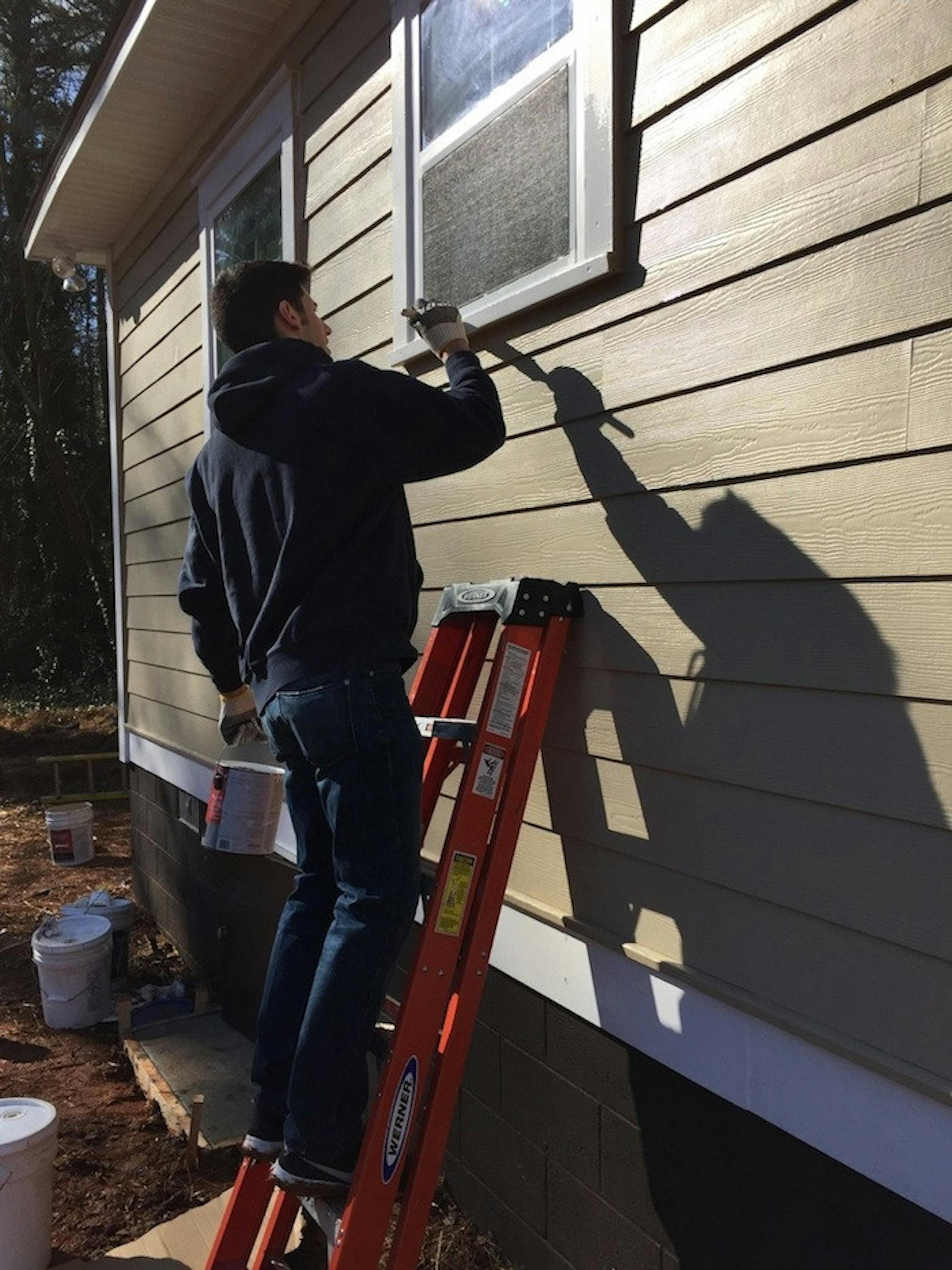 College senior David Bailey paints the exterior of the house he helped build for Lashunda McNabb, an Emory Starbucks barista. | Photo courtesy of David Bailey