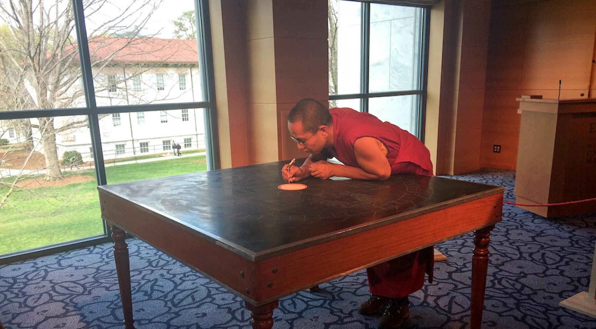 A Tibetan monk is outlining the Mandala painting. Photo by Julia Mulliez.