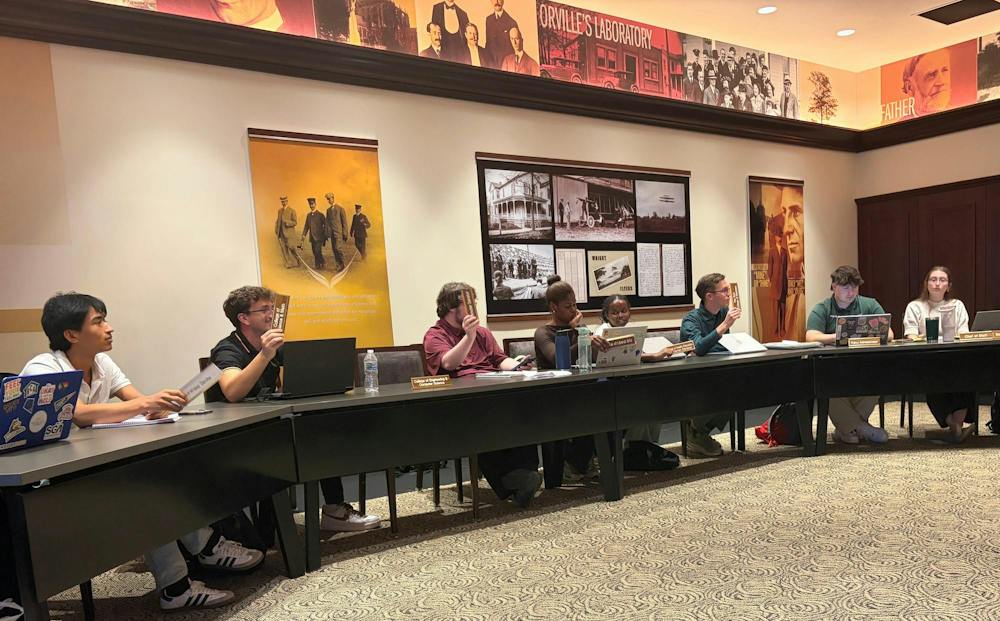 SGA sitting at a table, holding up nametags 