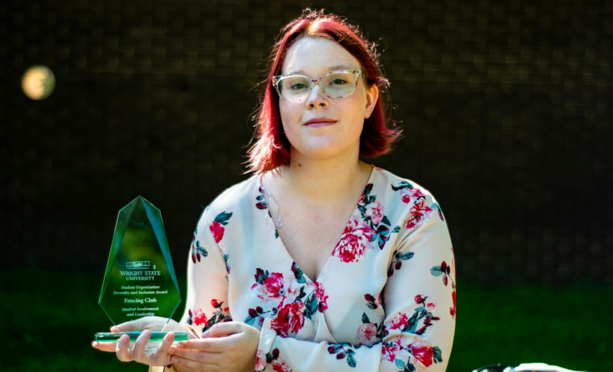 Student Molly Foster holding up an award the Fencing Club had won in 2020